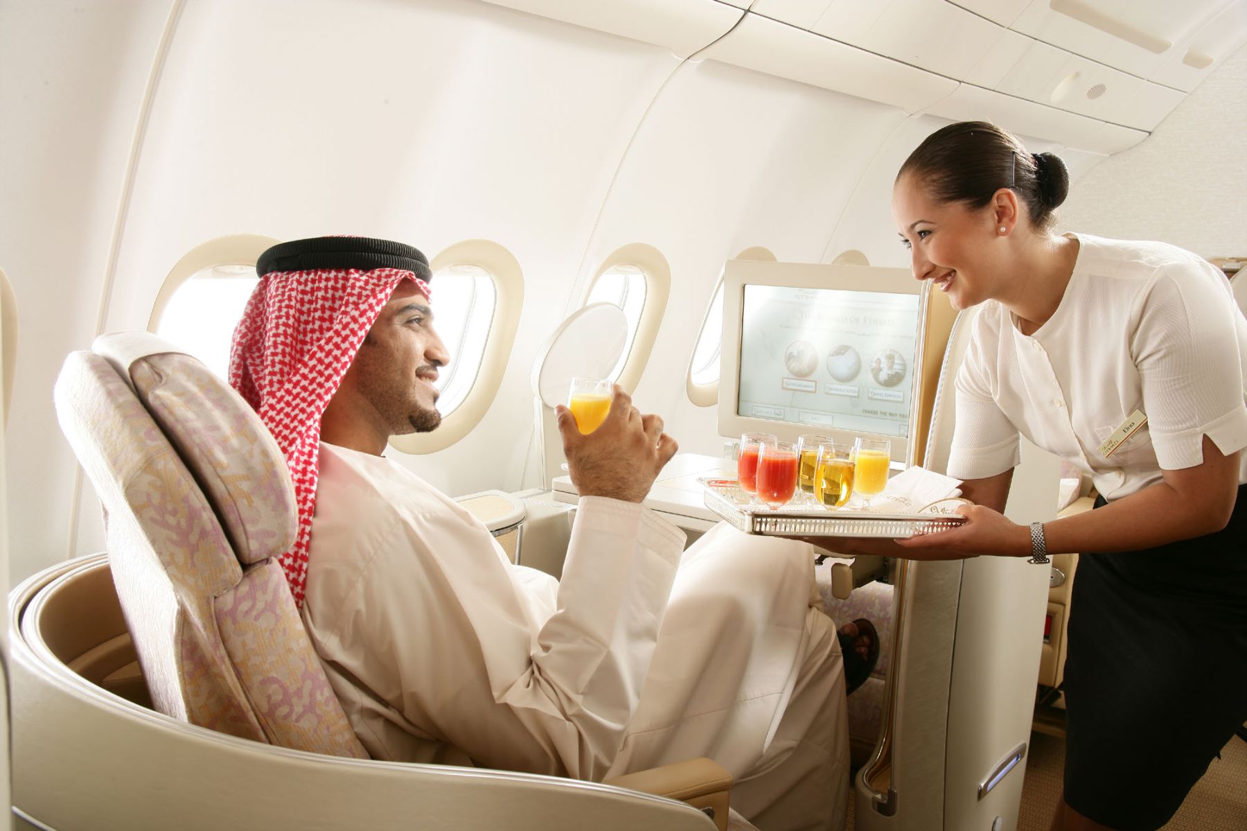 a woman serving drinks to a man in an airplane