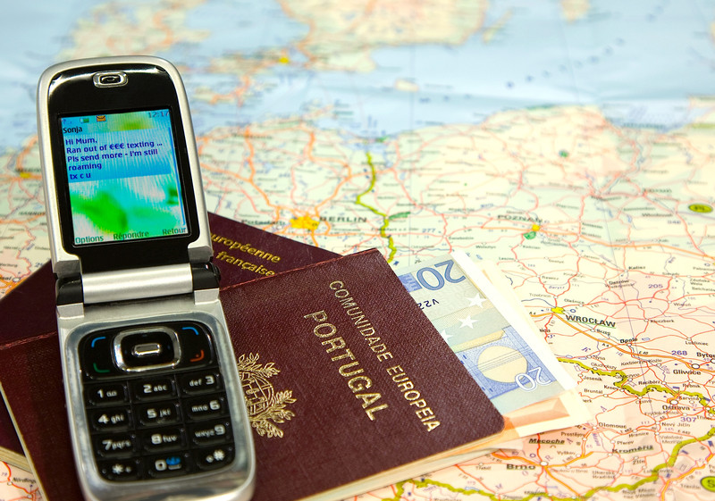 a cell phone and passport on a map