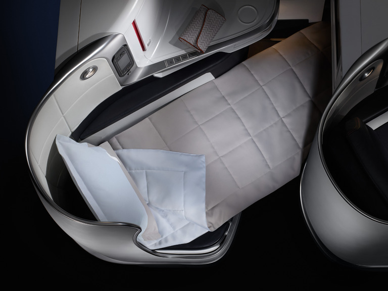 an airplane seat with a pillow and a blanket