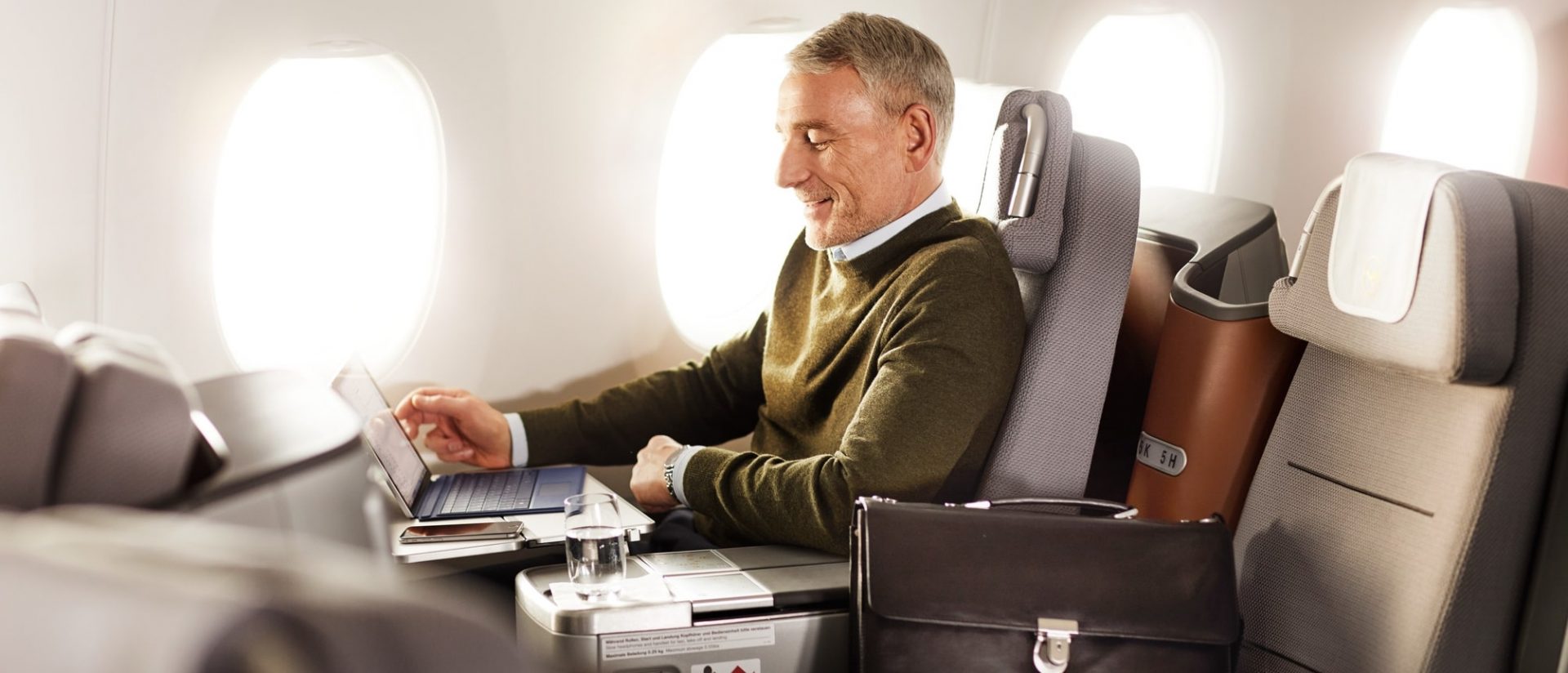 a man sitting in an airplane using a laptop