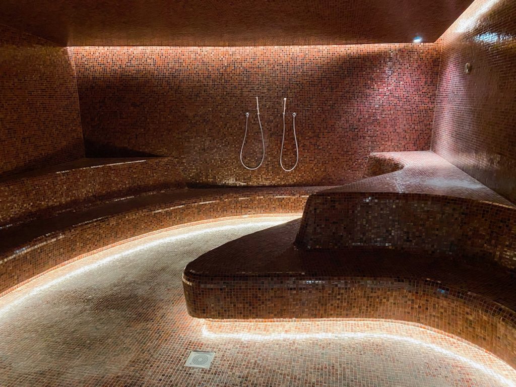 a shower room with a curved bench and a tile floor